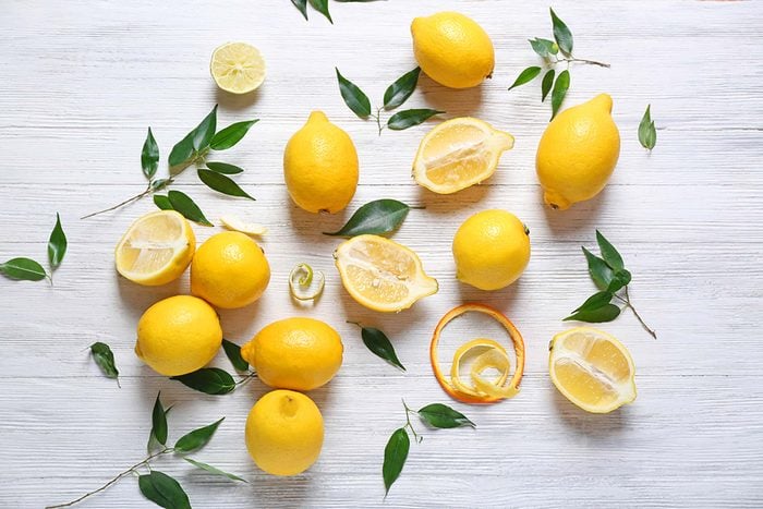 artistic arrangement of whole and halved lemons with leaves