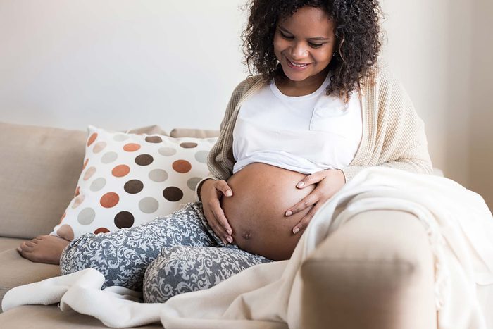 pregnant woman sitting on a couch and holding her belly