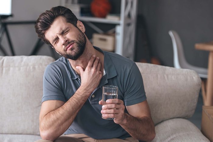 man with sore throat, holding glass of water