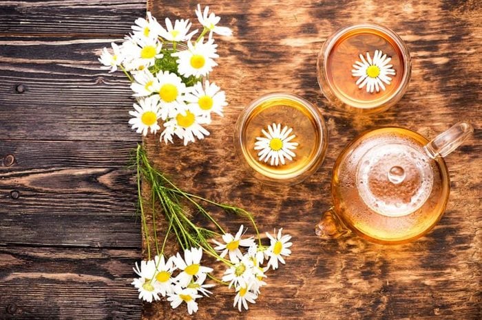 Chamomile blossoms on a table and floating in tea