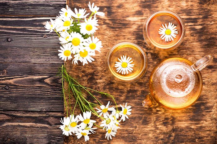 Chamomile blossoms on a table and floating in tea