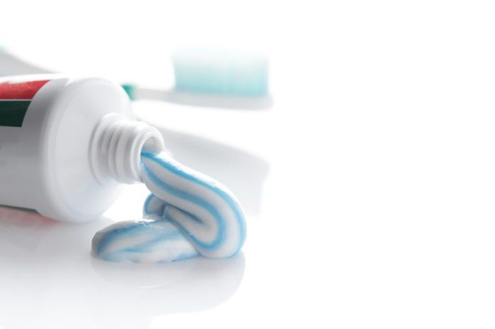 an open tube of toothpaste with a swirl of toothpaste oozing out