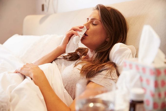 sick woman in bed with tissues