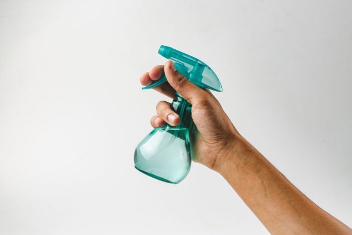 hand holding plastic spray bottle on gray background