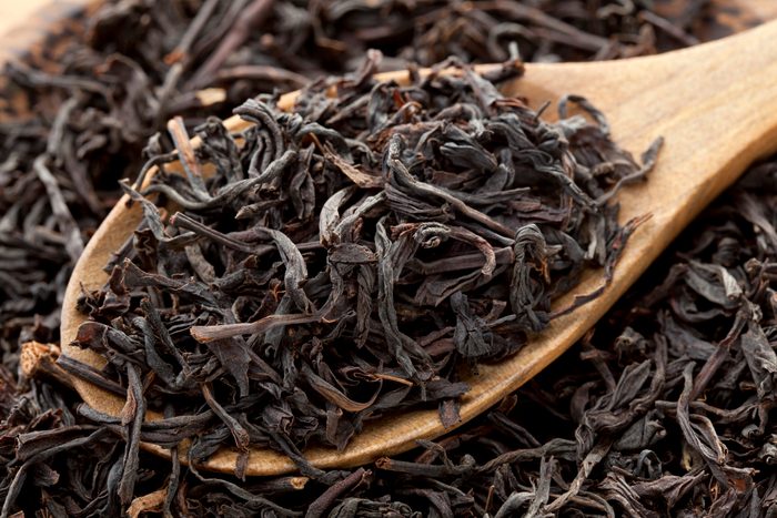 dry black tea in wooden spoon close up