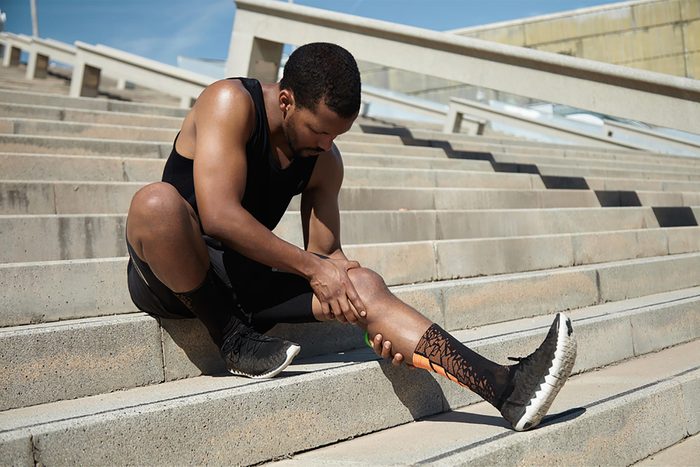 African-American man in workout gear clutching his left calf