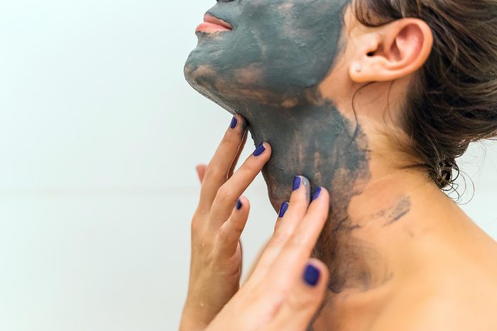 Woman applying dark green Bentonite-Clay mask