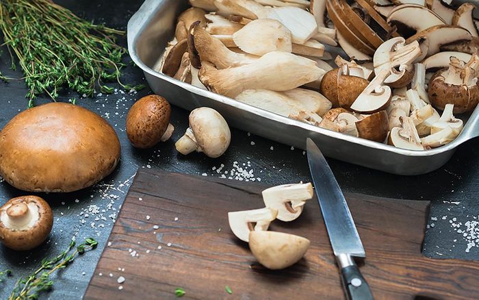 Mushrooms cut and whole, with a cutting board and knife