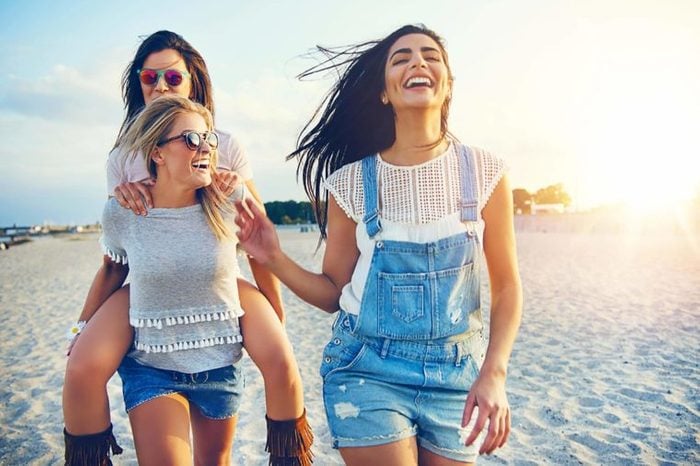female friends laughing and walking on the beach
