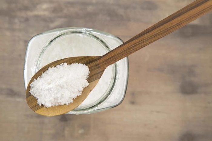 glass jar of baking soda with a wooden spoonful on top