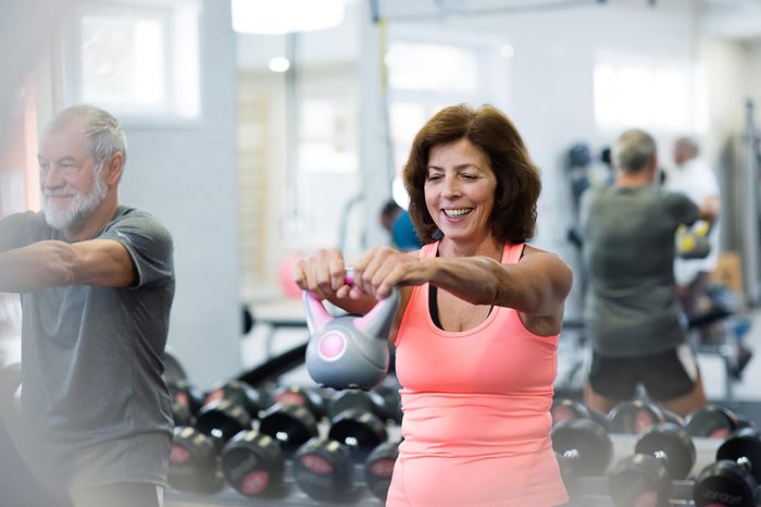 middle-aged man and woman lifting a kettle bell