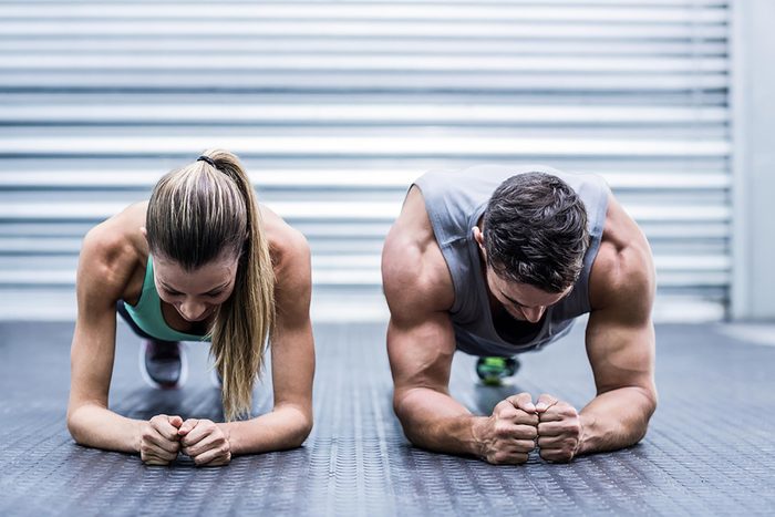 Fit man and woman holding a plank position