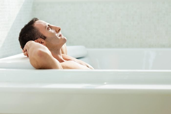 man soaking in tub with hands behind his head