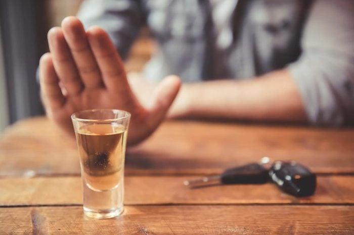 person turning down alcohol in a shot glass