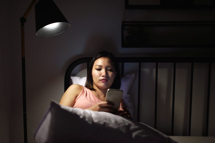 woman using smartphone in bed at night