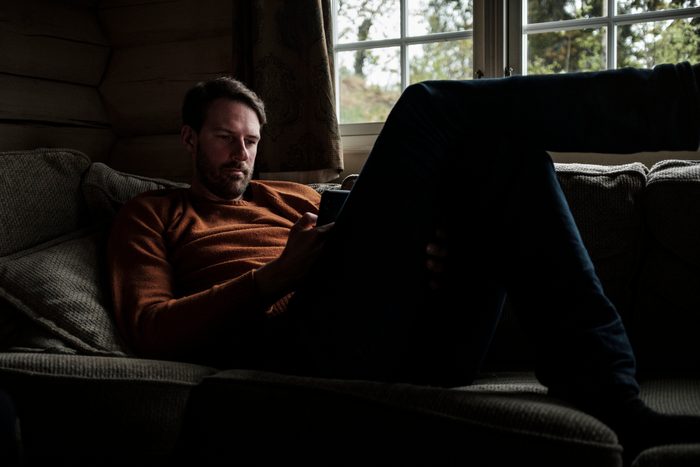 man sitting on sofa looking at smartphone device