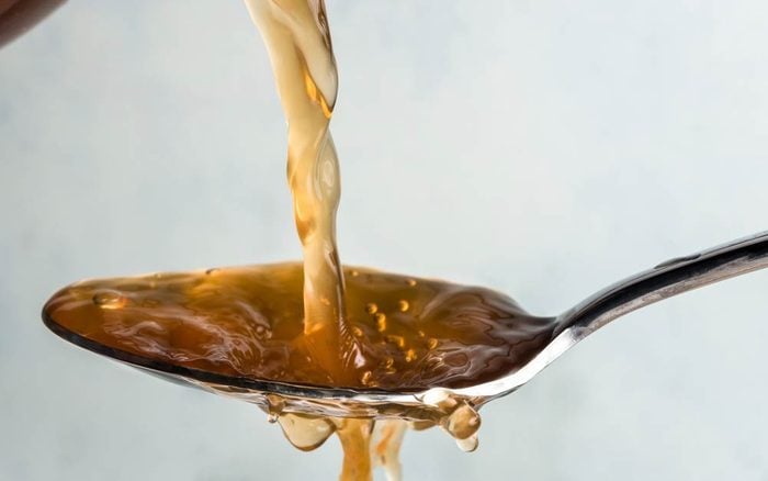 Apple cider vinegar being poured onto a tablespoon