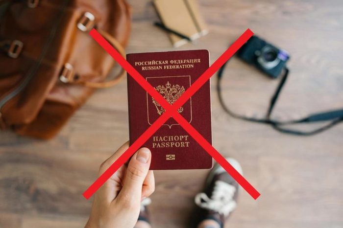 A person holding a passport with an X through it.