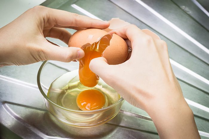 woman cracking eggs into a bowl