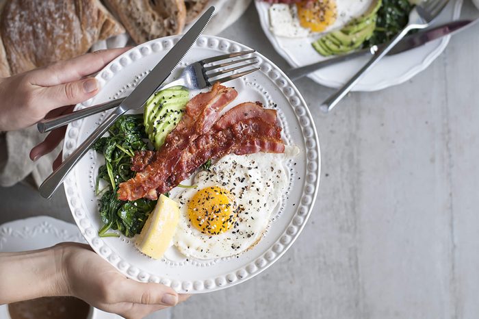 bacon, eggs, avocado, and spinach on a white plate