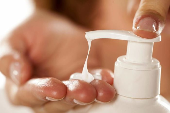 Hand pressing down on a pump bottle of lotion