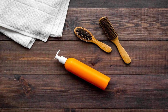 hair brushes, towel, and pump bottle on a dark wood surface