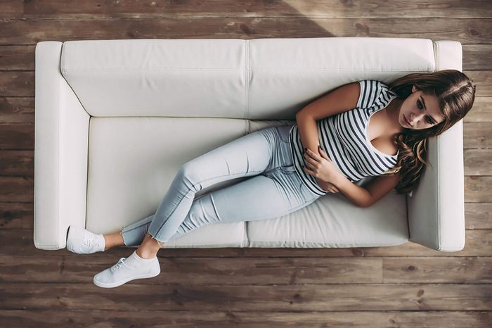 woman holding her stomach while lying on a couch
