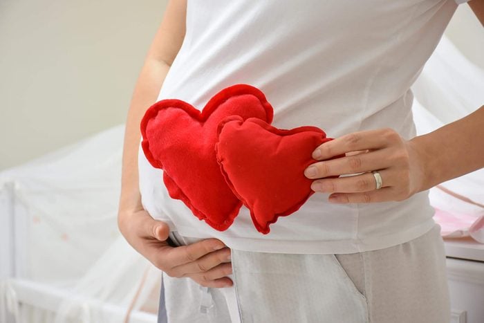 pregnant woman holding heart-shaped pillows by belly