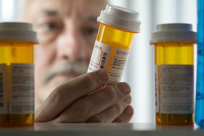 Man looking into medicine cabinet, holding pill bottle