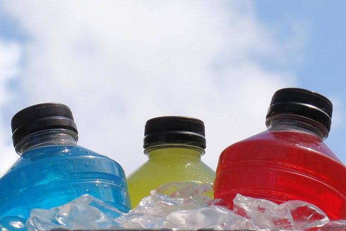 three bottles of colorful sports drinks on ice