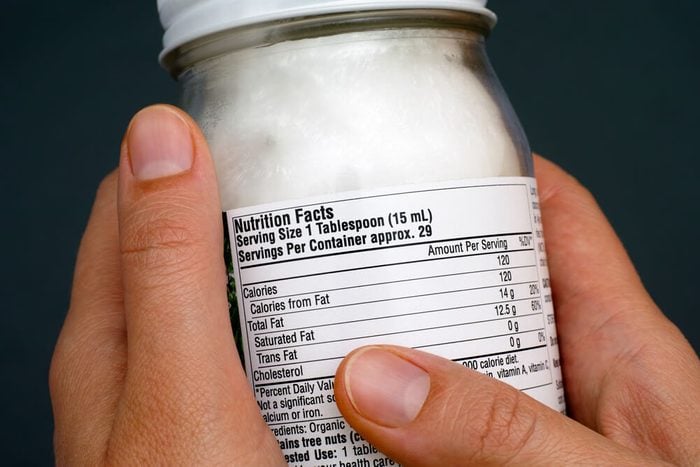 Reading a nutrition facts on organic coconut oil jar. Close-up.