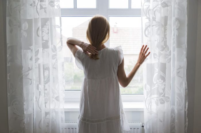 sad lady standing by a window