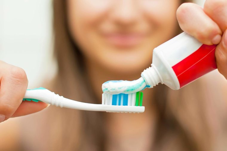 woman squeezing Toothpaste onto toothbrush