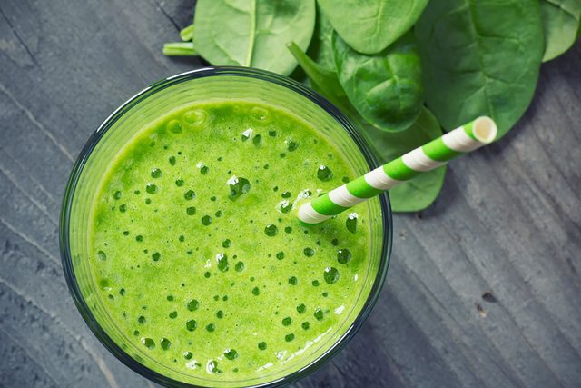 Spinach-smoothie in glass with straw
