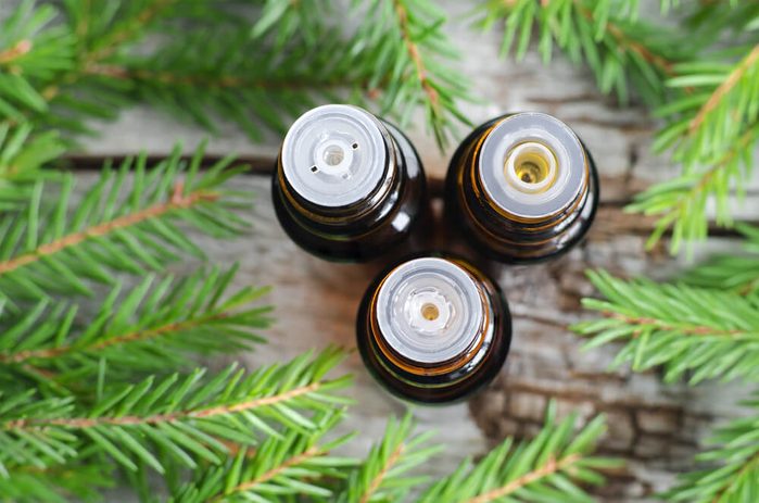 Three bottles of essential oil and fir branches. 