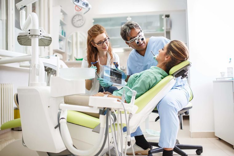 Dentist and assistant talking to patient in chair