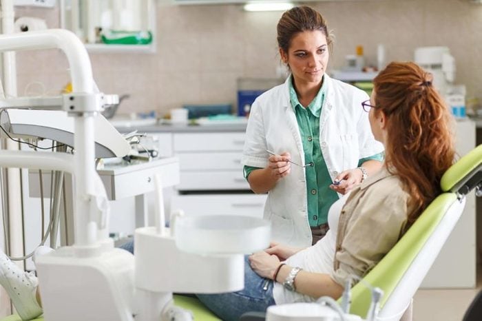 Female dentist discussing treatment with a patient in dental chair
