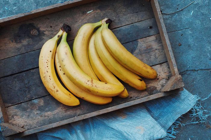 ripe yellow bananas in a wooden tray