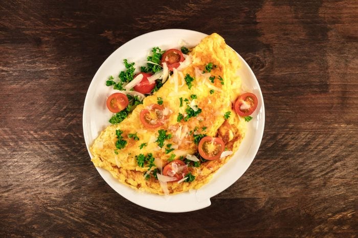 Heart healthy diet; A photo of an omelette with cherry tomatoes, parsley. and grated cheese, shot from above on a rustic wooden texture with a place for text