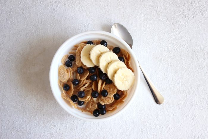 A Bowl of Cereal on white background. Breakfast Bowl of Cereal with Banana, Blueberries and Milk. Eating cereal. Healthy breakfast food.