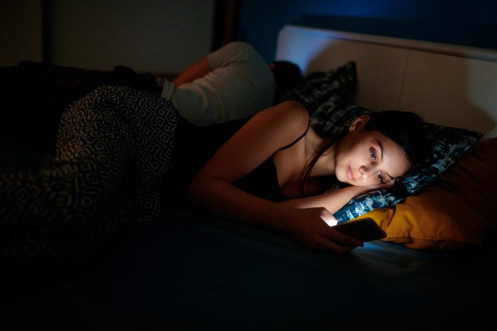 woman can't sleep checking her phone in bed