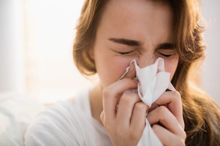 girl with runny nose blowing her nose into tissue