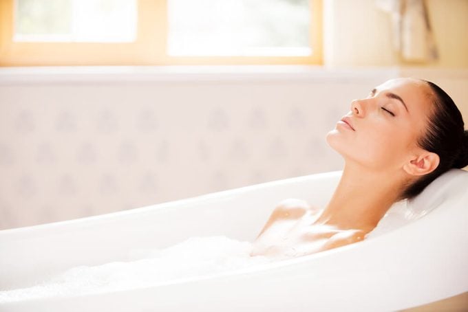 Woman keeping eyes closed while enjoying luxurious bath 