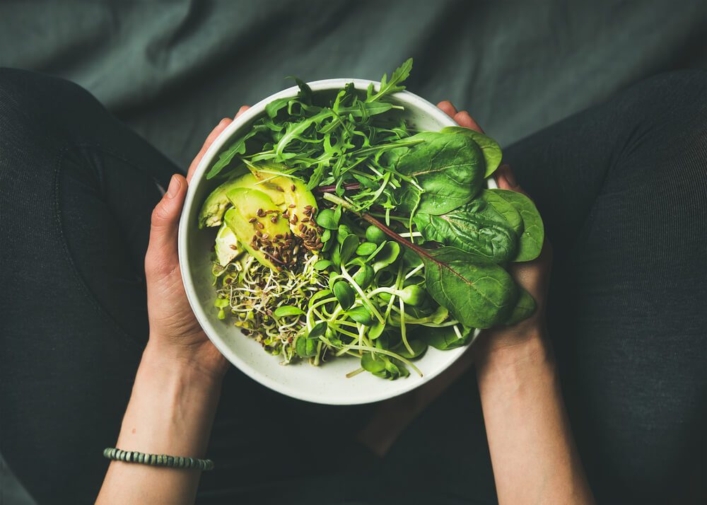 bowl with spinach, arugula, avocado, seeds and sprouts