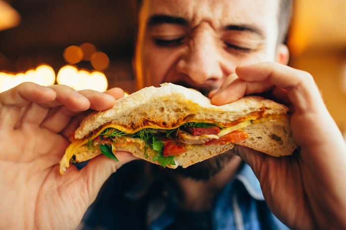 Man in a restaurant eating a flatbread sandwich