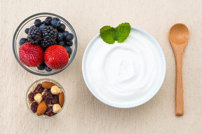 Bowl of Greek yogurt with berries and nuts on the side.