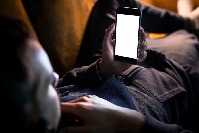 man on couch looking at phone