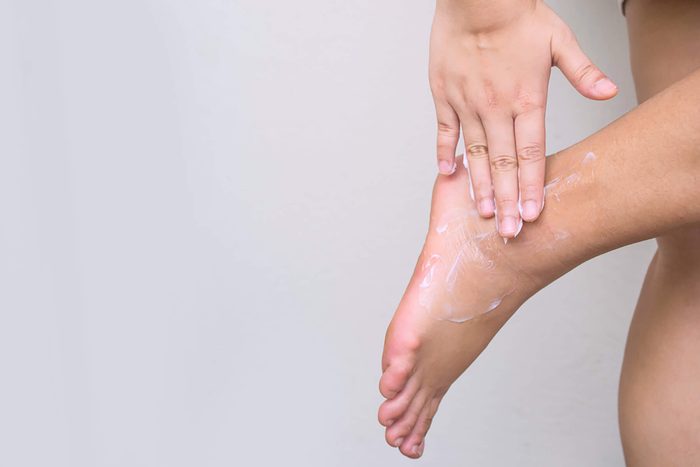 Woman-applying-cream-on-foot