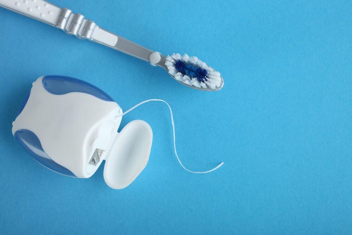 Dental floss and toothbrush on a blue background