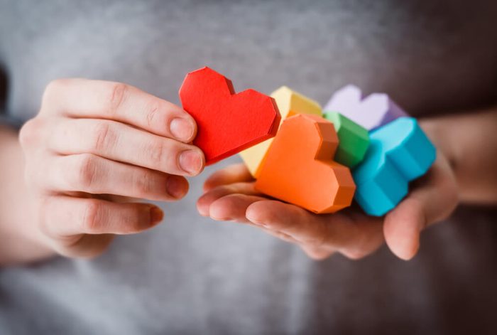 Hands holding rainbow paper hearts
